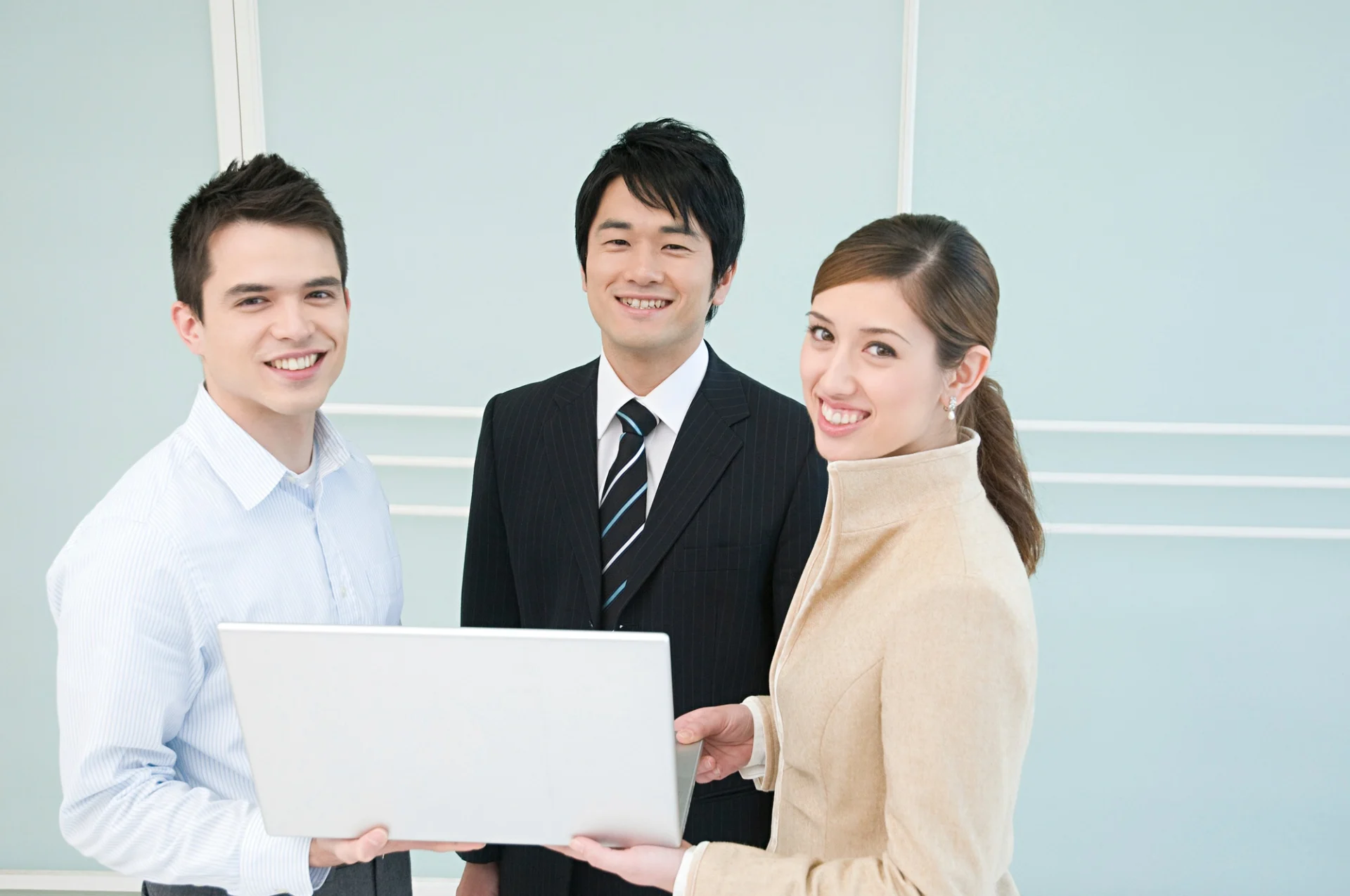 Three professionals sharing a moment of collaboration over a laptop.